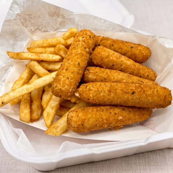 Golden-brown mozzarella sticks and french fries in a white takeout container lined with parchment paper.